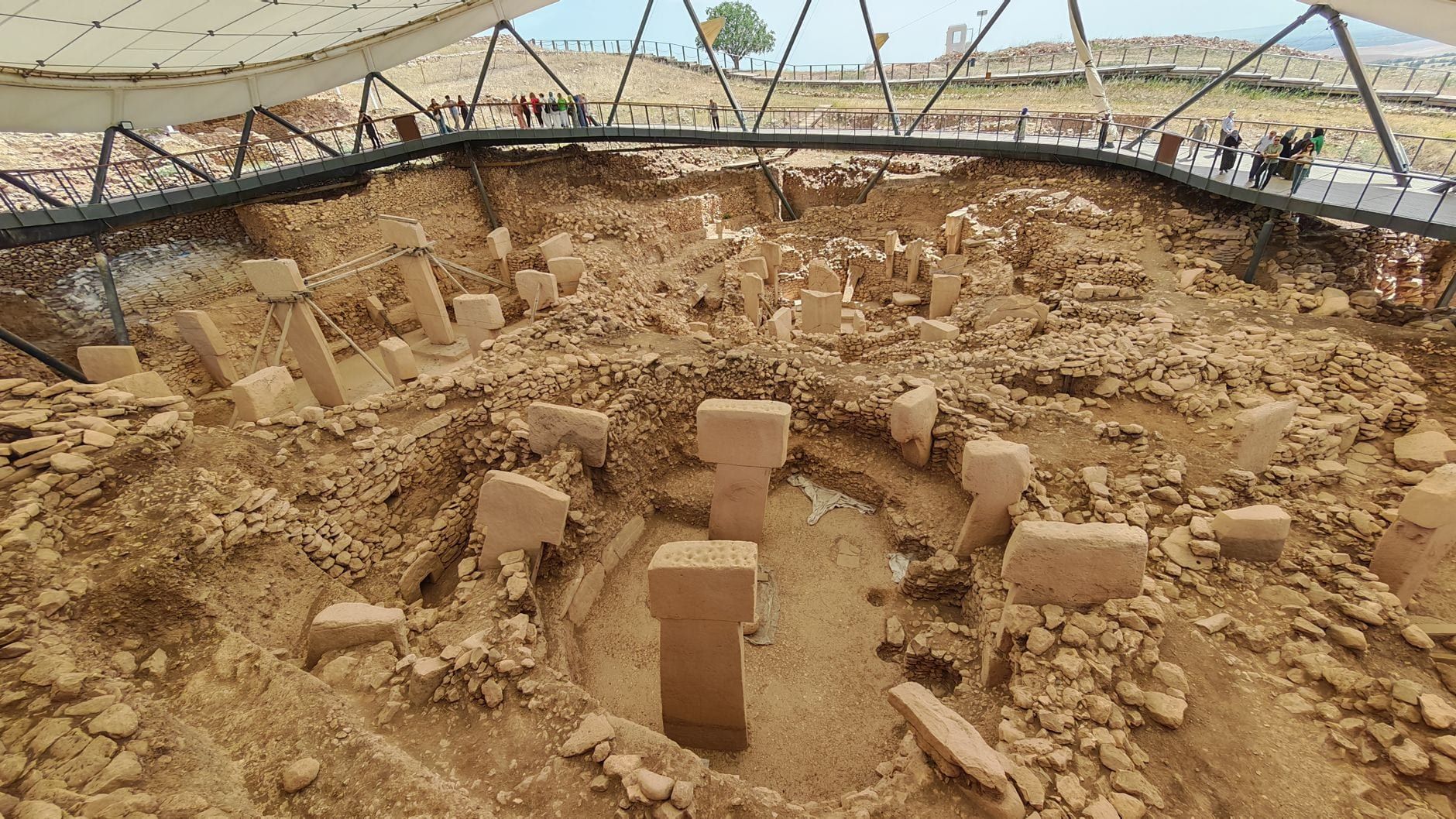 Wide view of the excavated prehistoric stone enclosures and T-shaped pillars at Göbekli Tepe under the protective canopy.