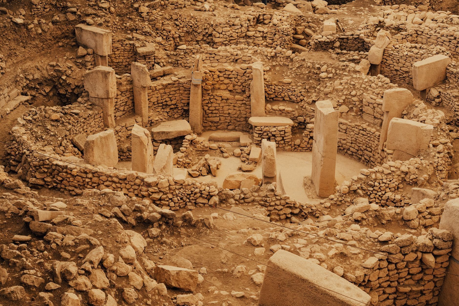 Elevated view of an excavated circular stone enclosure featuring massive T-shaped limestone pillars at Göbekli Tepe.